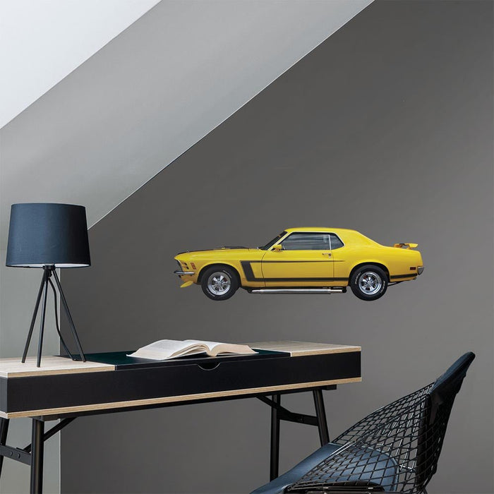 36 inch Yellow mustang muscle car decal installed on a gray wall above a desk with a lamp and chair.